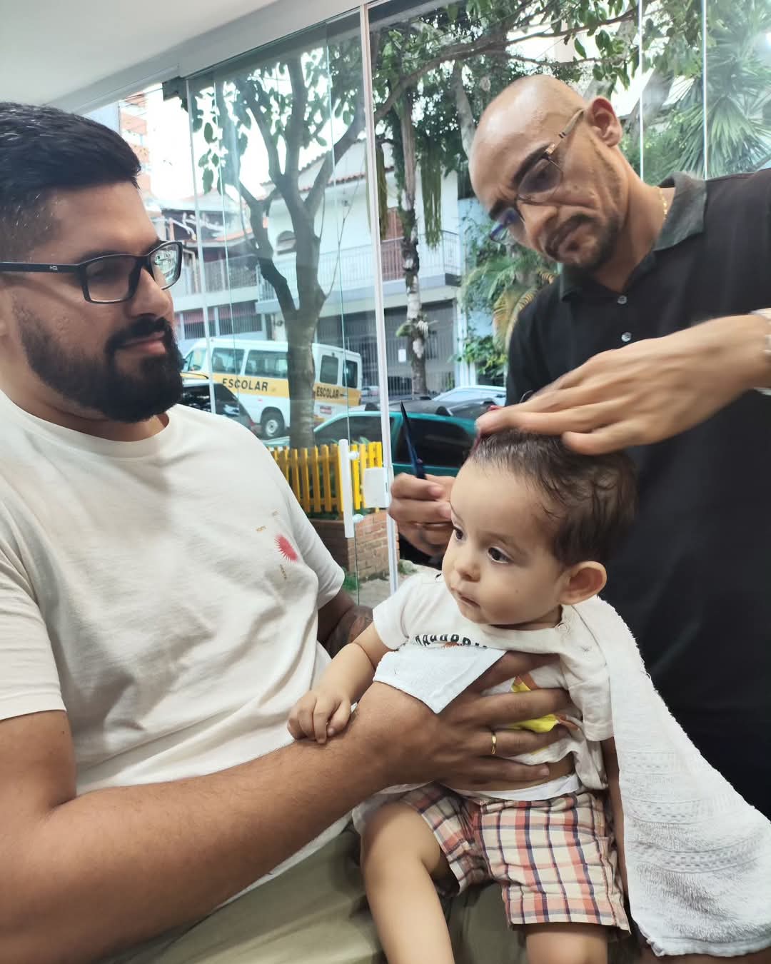 Corte de cabelo em bebê no colo do pai